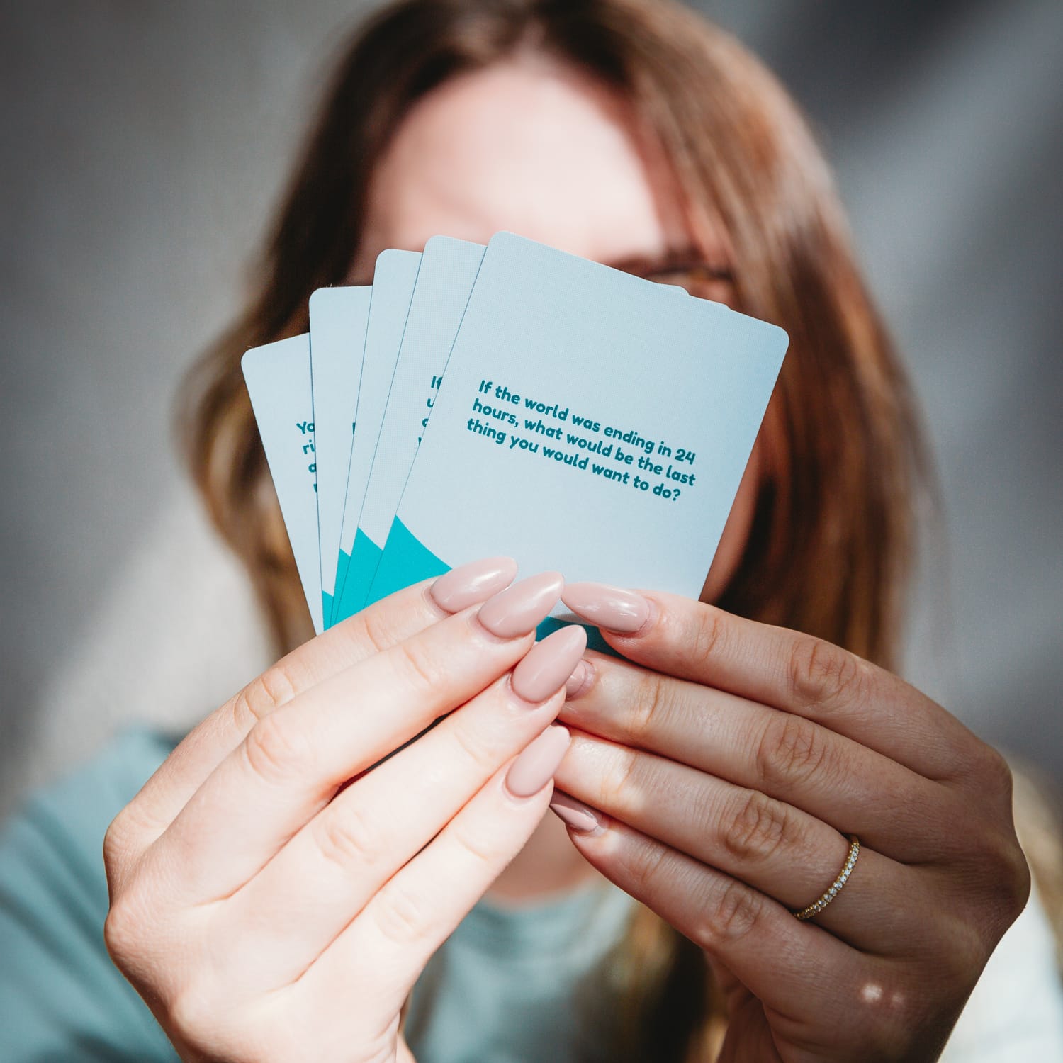 Girl holding cards from 141 Outrageous Conversation Starters for Couples card game